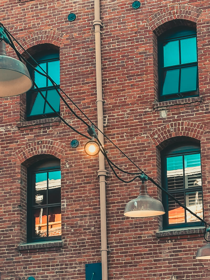 Brick wall with lamps and teal-lit windows