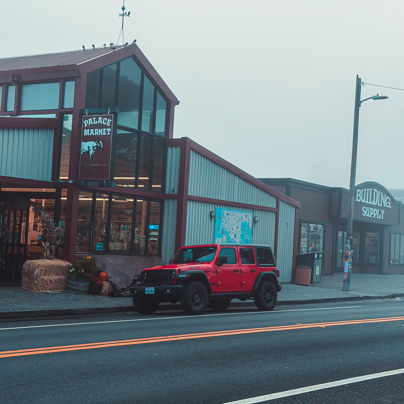 Small-town market with a red Jeep parked outside