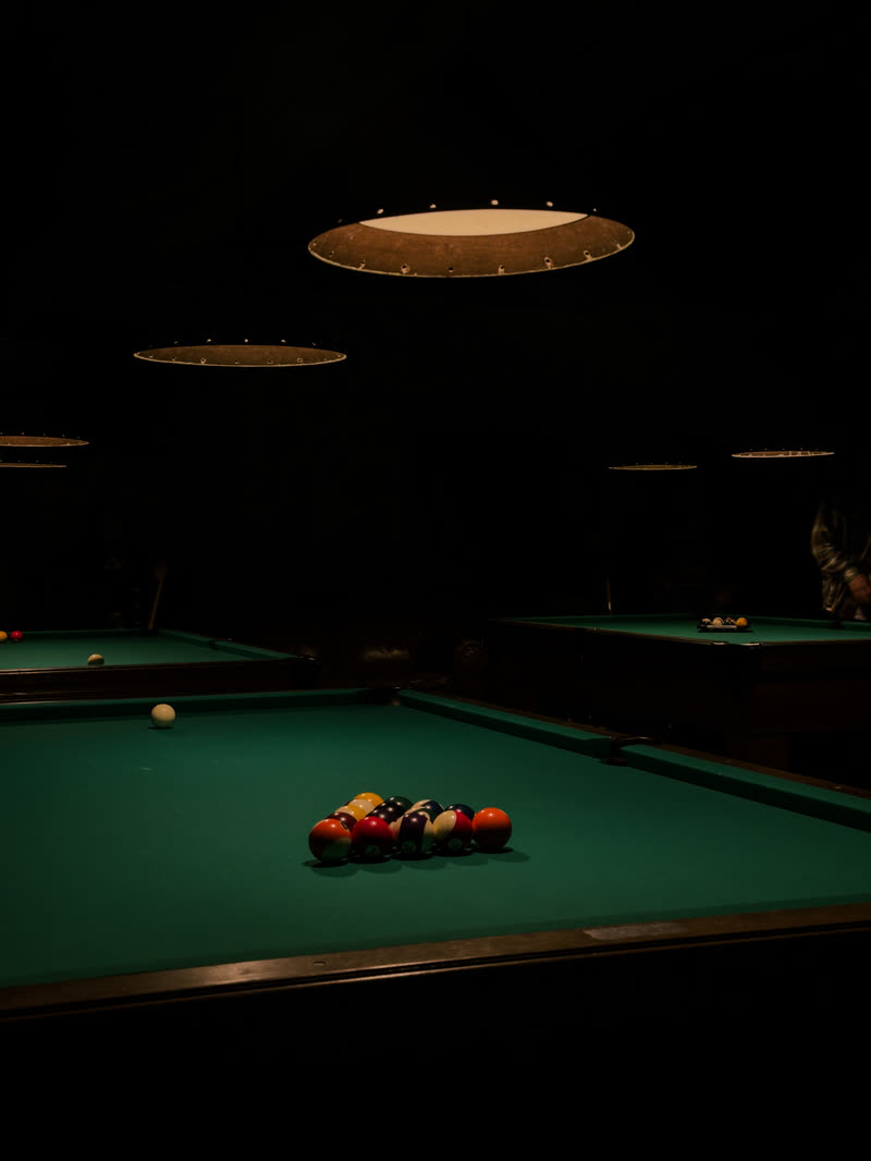 Pool table under a single lamp in a dark hall